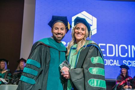 Image of Dr. Jacob Ribbing and Dr. Rachel Terrill with her award for Faculty Excellence at the 2024 SIU DMSc Hooding Ceremony